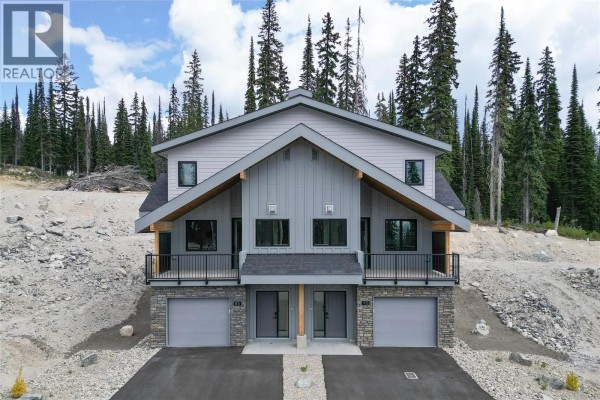 Front view of duplex with matching entrances, garages, and mountain surroundings. - 85 Creekside Trail, Big White