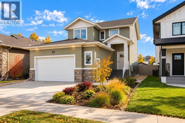 Front exterior of a green house with a covered porch, garage, and manicured lawn. - 85 Crestview Boulevard, Sylvan Lake