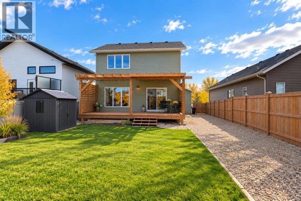 Backyard view of a green house with a wooden deck, pergola, shed, and wooden fence. - 85 Crestview Boulevard, Sylvan Lake
