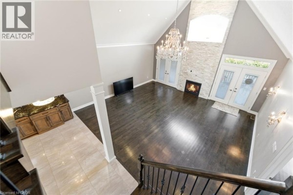 Living room with vaulted ceiling, stone fireplace, and chandelier - 85 Hillcroft Drive Stoney Creek