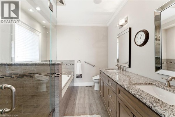 Kitchen island with sink, granite counters, gas range, fireplace, and staircase - 85 Hillcroft Drive Stoney Creek