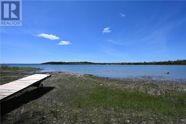 Wooden plank dock extending onto a shallow, clear lake under a bright blue sky. - 85 Leason Bay Trail, Assiginack