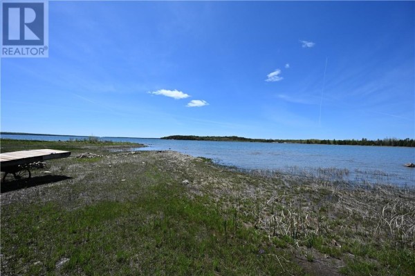 Expansive view of a blue lake with a treed shoreline and a wooden dock. - 85 Leason Bay Trail, Assiginack