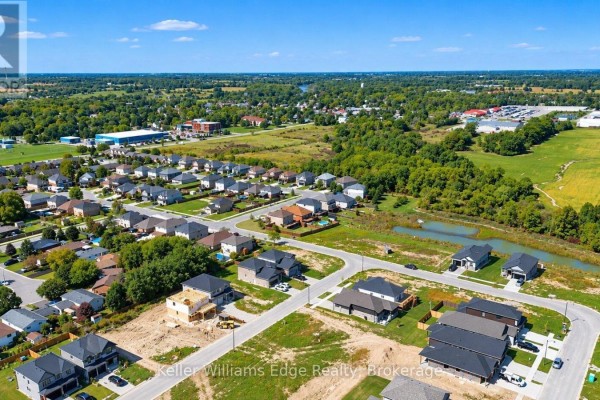 Aerial view of a suburban neighborhood with streets, homes, trees, and distant fields. - 85 Pike Creek Drive, Haldimand