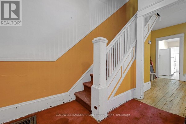 Interior hallway with orange walls and a carpeted staircase leading up. - 85 Richmond Road, Ottawa