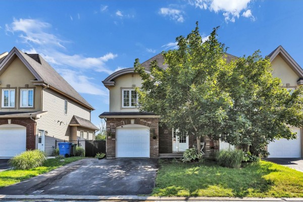Street view of a townhouse complex showing a central unit with a brick base and beige siding. - 85 Rue De La Pointe-taillon, Gatineau