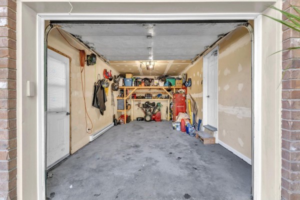 Interior of a two-car garage with concrete floor, storage shelves, and various tools and equipment. - 85 Rue De La Pointe-taillon, Gatineau