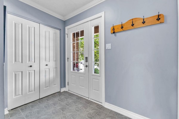 Entrance hall with light blue walls, tiled floor, white double closet doors, and a glass-paneled front door. - 85 Rue De La Pointe-taillon, Gatineau