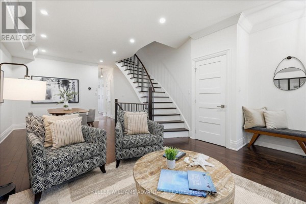 A living room with patterned armchairs, a wooden coffee table, and a curved staircase. - 85 Sarah Ashbridge Avenue, Toronto