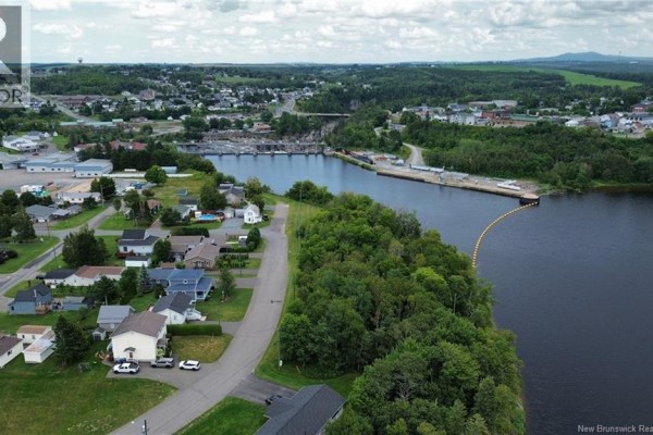 Aerial view of the backyard featuring a pool, patio area, and neighboring properties. - 85 Taylor Street, Grand Sault/grand Falls