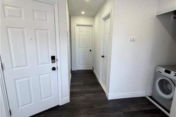 Interior hallway with dark flooring, white doors, and a stacked washer and dryer unit. - 85 Wilson Street Unit# 3, Hamilton