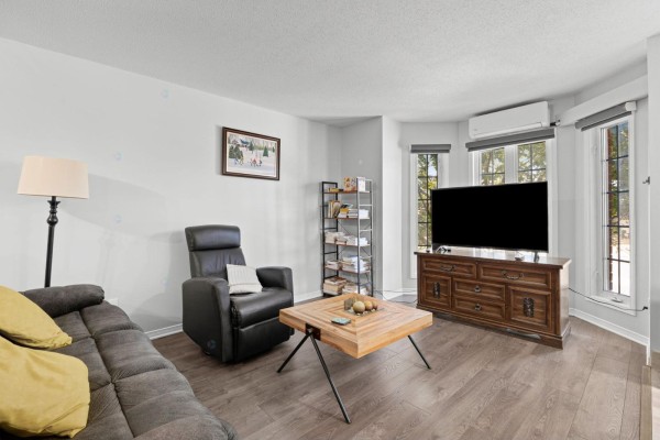 Living room with gray sofa, black leather recliner, wooden coffee table, and television on a dark wood console. - 850 Boul. St-rené O., #2, Gatineau