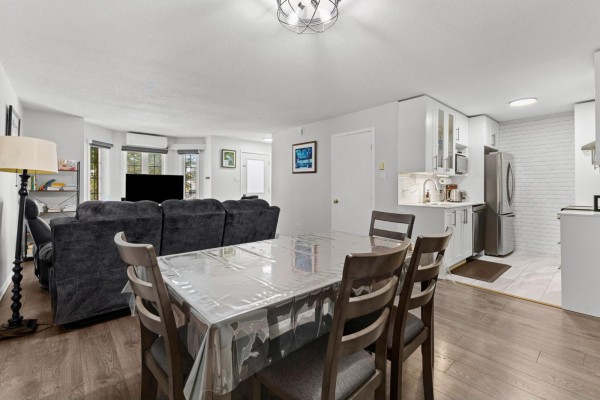 Dining table with four chairs covered in clear plastic, adjacent to the living room and kitchen area. - 850 Boul. St-rené O., #2, Gatineau