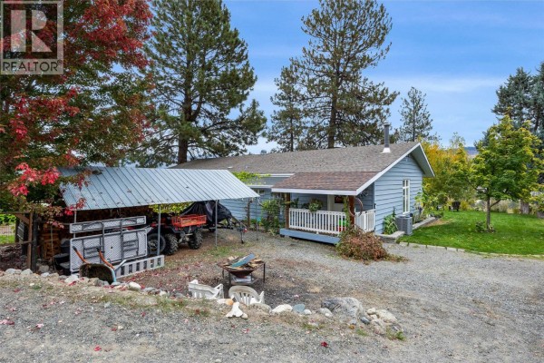 Light blue house with a covered carport holding an ATV and outdoor equipment. - 850 Inskip Road, Kamloops