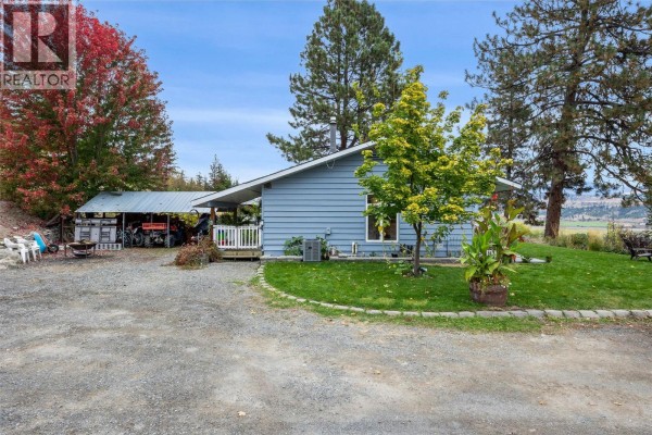 Side view of a light blue house with a green lawn and trees. - 850 Inskip Road, Kamloops