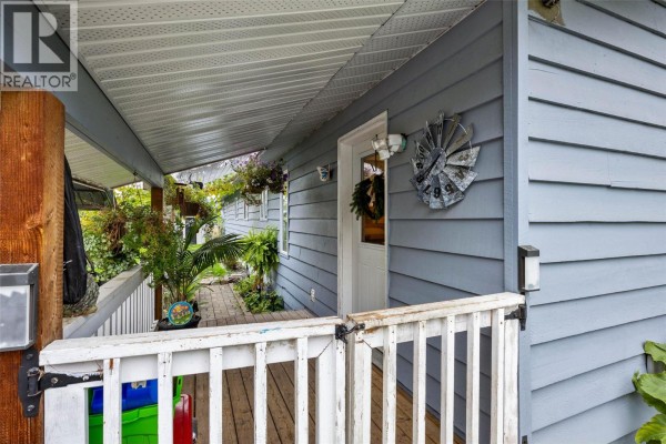 Covered front porch with white railings and hanging plants. - 850 Inskip Road, Kamloops