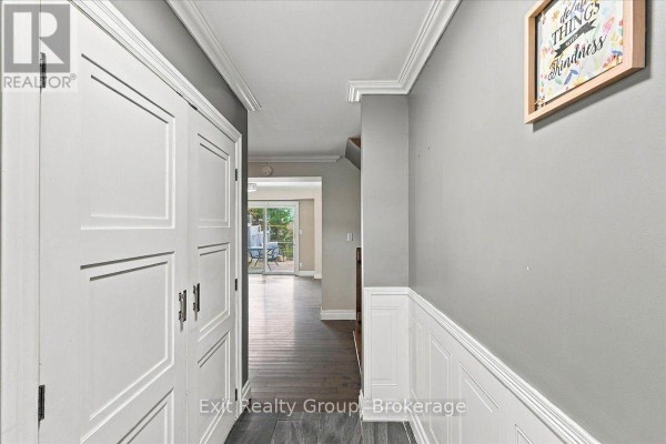 Interior hallway with grey walls, white wainscoting, dark wood floor, and double closet doors. - 850 Littlestone Crescent, Kingston
