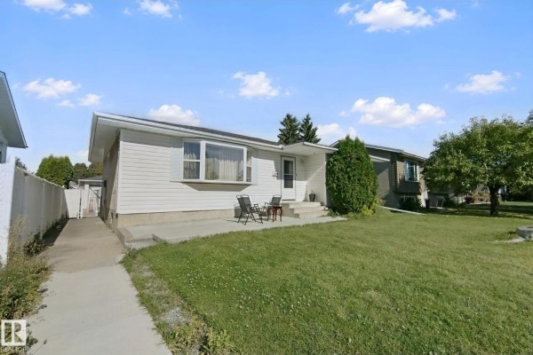 View of the front side of a white bungalow, showing the driveway, lawn, and front entrance. - 8508 149a Av Nw, Edmonton