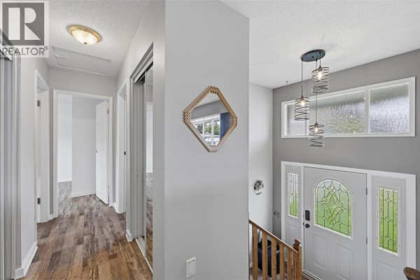 Interior view of a bright entryway with a staircase, front door with sidelights, and a long hallway. - 851 Sumac Place, Kamloops