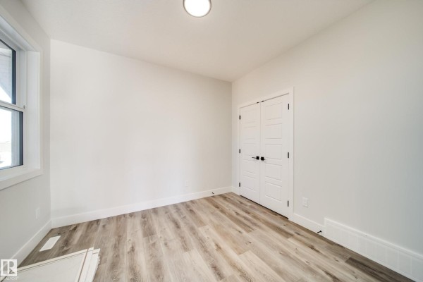 Empty room with white walls, a window, and double doors with a modern design. - 8515 183 Av Nw, Edmonton