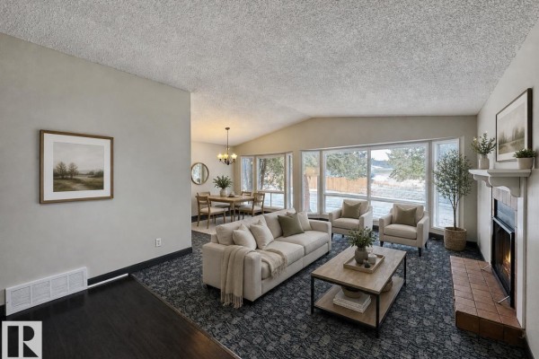 Living area with patterned carpet, fireplace, and natural light from windows. - 8516 190 St Nw, Edmonton