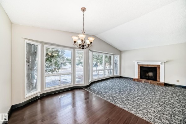 Open living space with fireplace, chandelier, and access to kitchen area. - 8516 190 St Nw, Edmonton