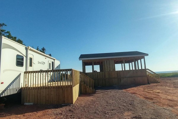 Exterior of a covered wooden deck attached to a trailer, with a separate gazebo. - 8519 Route 14, Campbellton