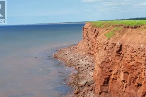 Close-up view of a red sandstone cliff edge meeting the ocean water. - 8519 Route 14, Campbellton