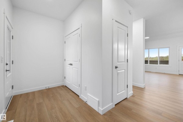 Empty bedroom with gray carpet, white walls, and a single window overlooking trees. - 8520 183 Av Nw, Edmonton