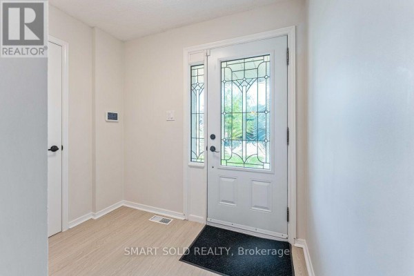 Interior view of a bright entryway with a white door and sidelight. - 853 Apple Gate Court, Mississauga