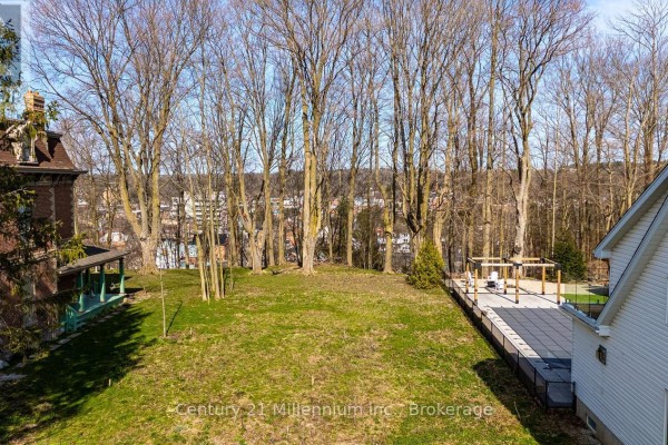 View of the grassy lot looking towards trees and neighboring houses, with a patio visible. - 855 4th Avenue A West Avenue, Owen Sound