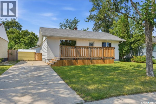 Front view of the house, showing the driveway, lawn, and a small yellow shed. - 856 Forget Street, Regina