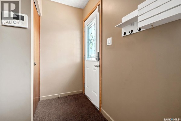 Living room with wood floors and a ceiling fan, open to the kitchen area. - 856 Forget Street, Regina