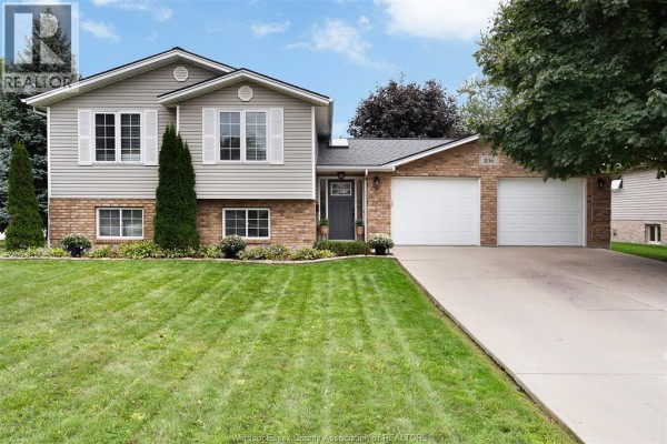 Two-story house with grey siding, brick accents, a two-car garage, and a manicured lawn. - 856 Lawndale Avenue, Kingsville
