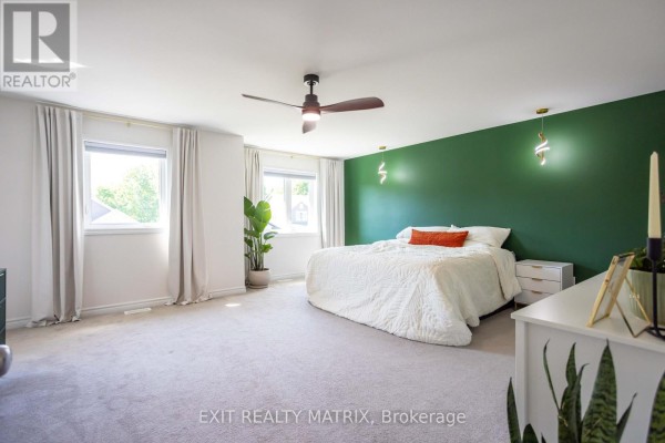 Bedroom with green accent wall, ceiling fan, and white bedding - 857 Cologne Street Russell