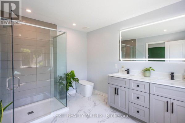 Modern bathroom with walk-in shower, double vanity, and illuminated mirror - 857 Cologne Street Russell