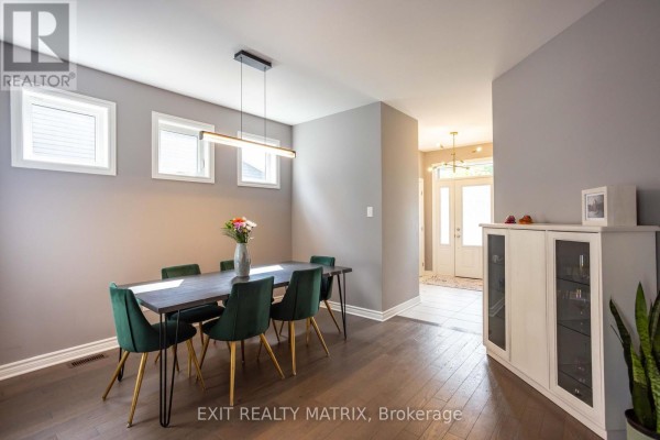 Dining room with dark wood table, green chairs, and modern light fixture - 857 Cologne Street Russell