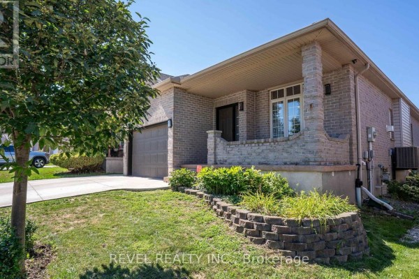 View of the front porch and brick exterior of a house with a lawn and walkway. - 857 Cresthaven Crescent, London South