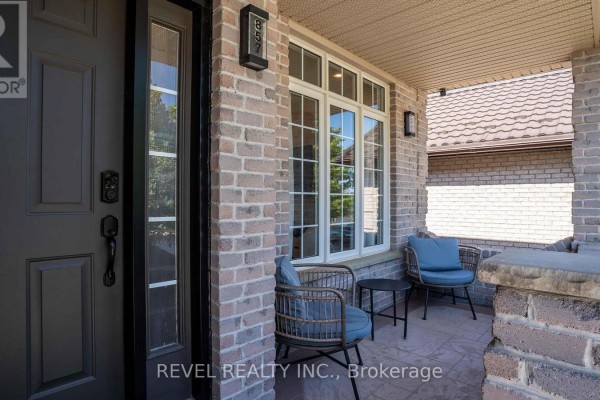 Close-up of the covered porch with seating, brick exterior, and front door at 857 Cresthaven Crescent. - 857 Cresthaven Crescent, London South