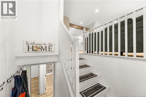Open-concept kitchen and living area with white cabinetry and stainless steel appliances. - 857 Mapleton Road, Moncton