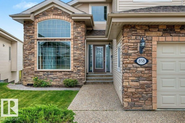 Close-up of the house entrance with a stone facade, arched window, and house number 858. - 858 Hodgins Rd Nw Nw, Edmonton