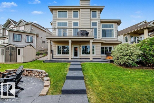 Rear view of the house showing the backyard, lawn, and walkout basement access. - 858 Hodgins Rd Nw Nw, Edmonton