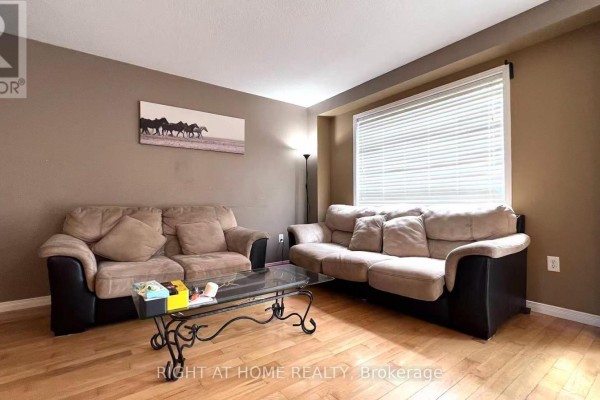 Living room with two beige sofas, a glass coffee table, and hardwood floors. - 858 Whetherfield Street, London North