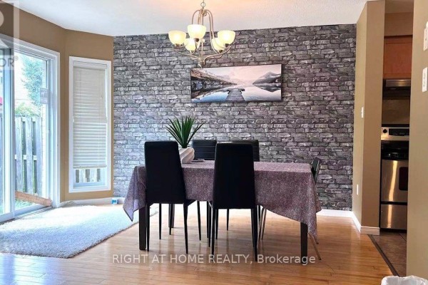 Dining area with a table set for four, a stone accent wall, and hardwood floors. - 858 Whetherfield Street, London North
