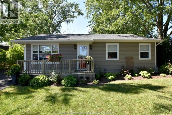 Front exterior of the beige vinyl-sided house with a wooden porch and landscaping. - 8585 James Street, Charing Cross