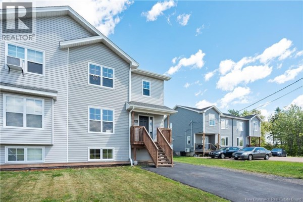 View of a light gray duplex with a covered entrance and wood stairs. - 859 Ryan Street, Moncton