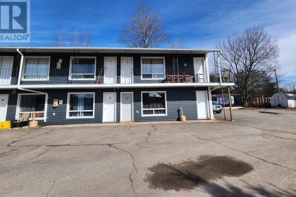 Rear exterior of a building with dark gray siding and red metal stairs. - 859 Trunk Rd, Sault Ste  Marie