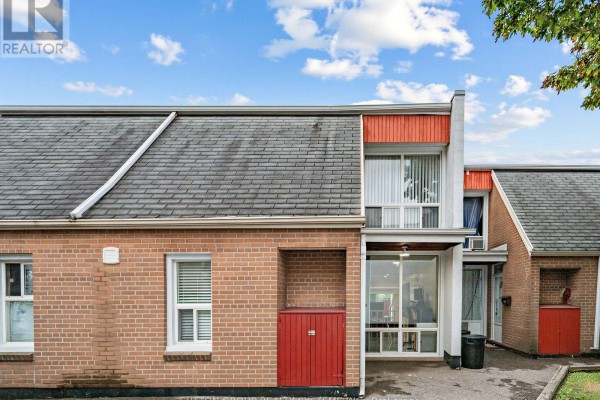 Close-up of townhouse exterior showing brickwork, red doors, windows, and peaked roof. - 86 - 2901 Jane Street, Toronto