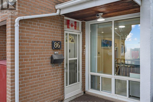 Front door area of the townhouse with a mail slot, number 86, and Canadian flag decal. - 86 - 2901 Jane Street, Toronto