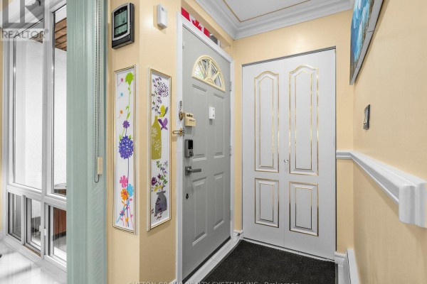 Interior entryway with pale yellow walls, grey front door, white double doors, and floral art. - 86 - 2901 Jane Street, Toronto